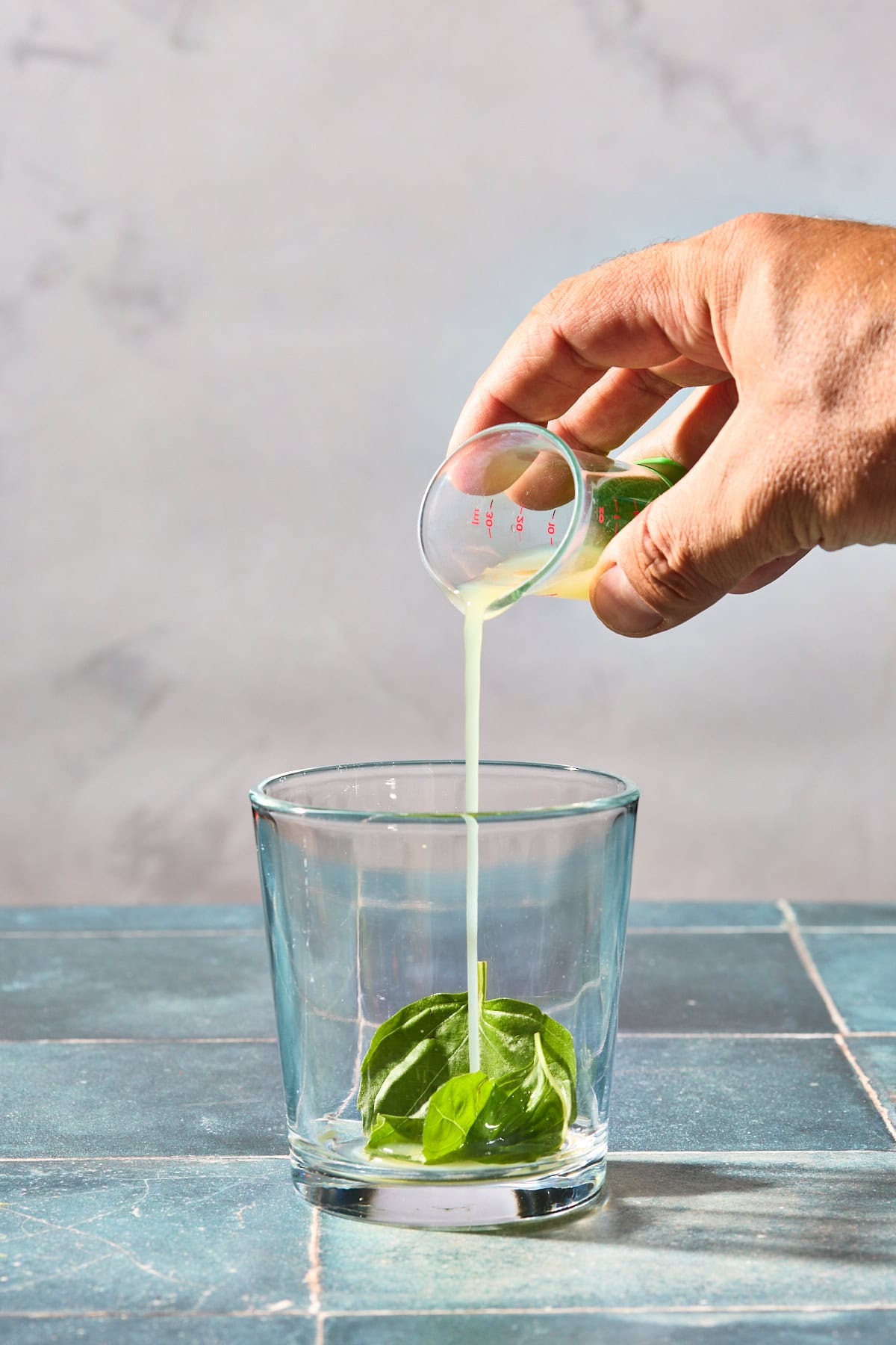 lime juice being poured into a glass with basil