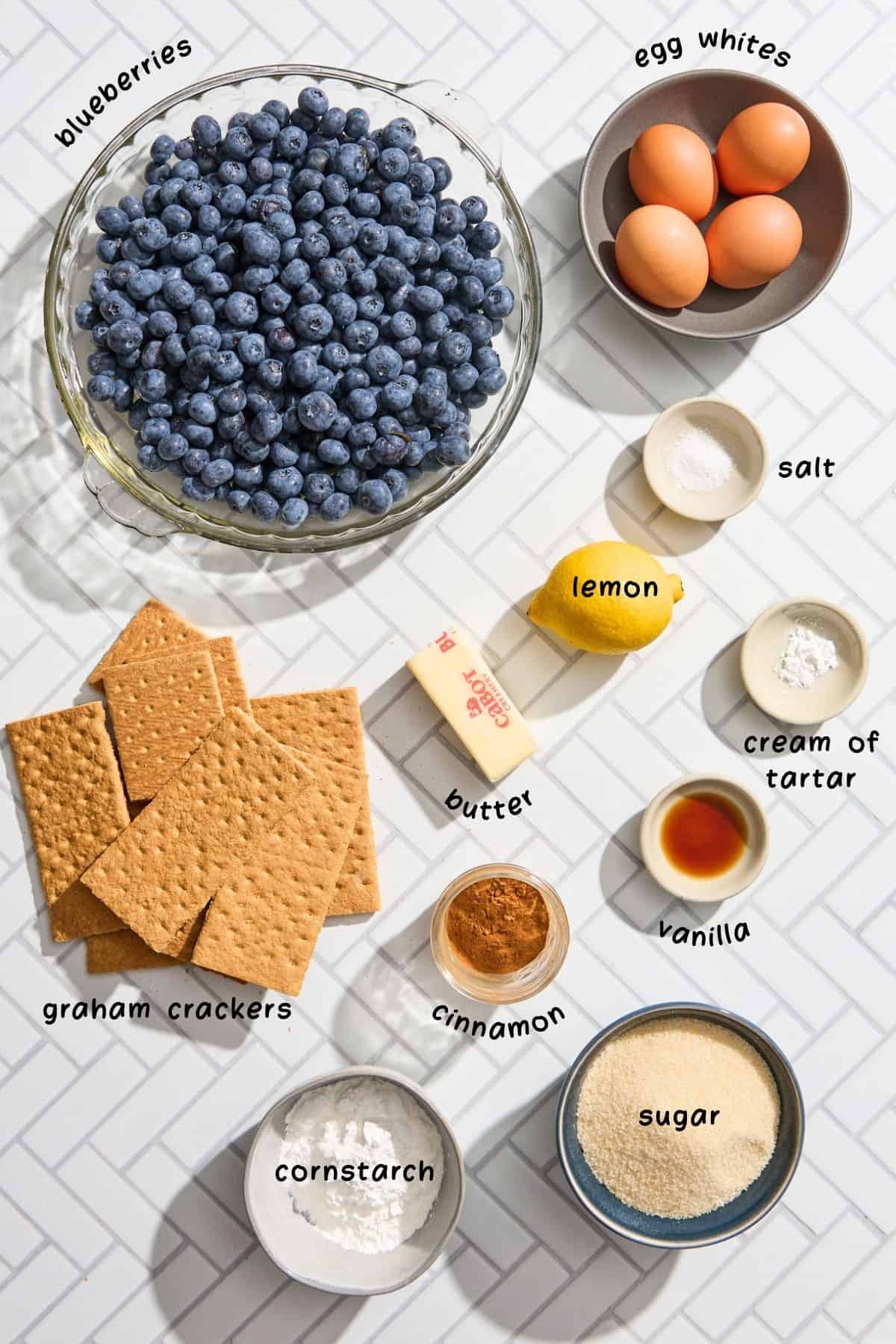 blueberries, graham crackers, eggs, and other ingredients for the pie recipe on a white counter
