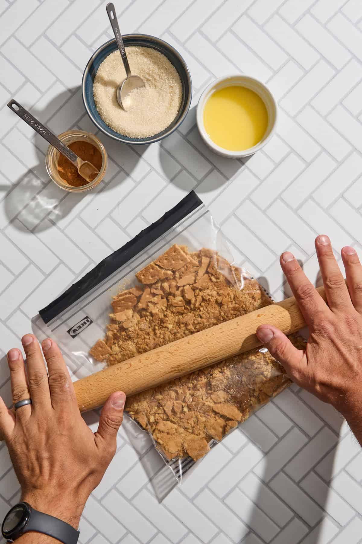 graham crackers being crushed in a plastic bag with a rolling pin