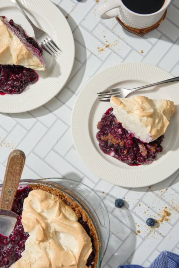 plates of blueberry pie with meringue with coffee on a white tiled counter