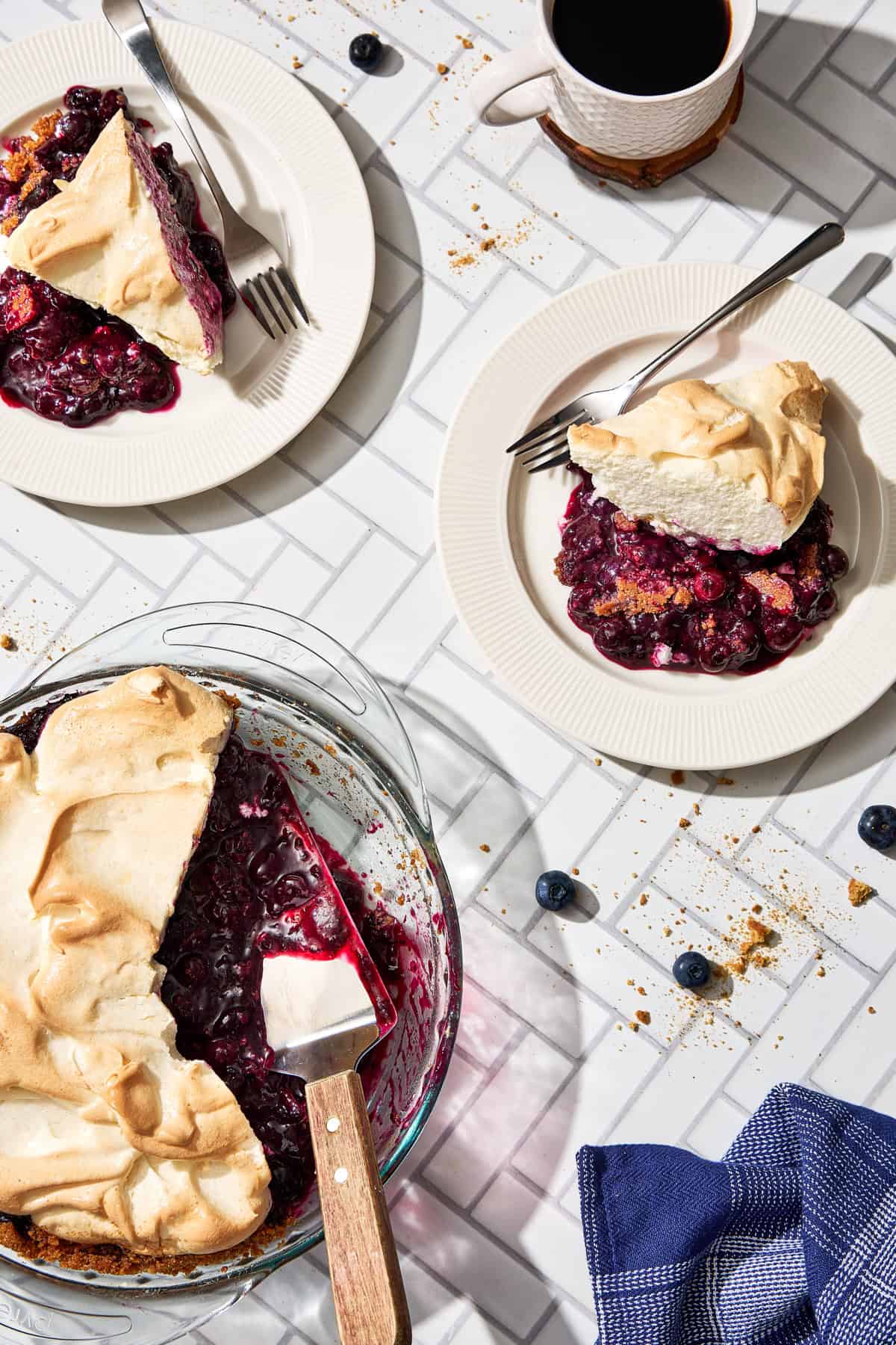 two pieces of blueberry pie topped with meringue and a plate of pie
