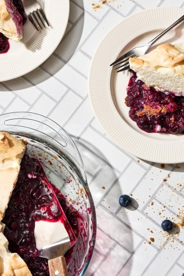 plates of blueberry meringue pie on a white counter with a coffee mug
