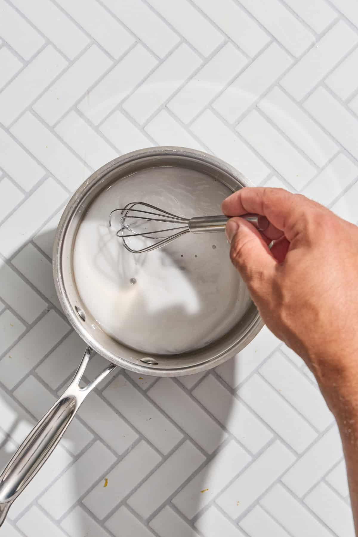 cornstarch and water being whisked in a small pan