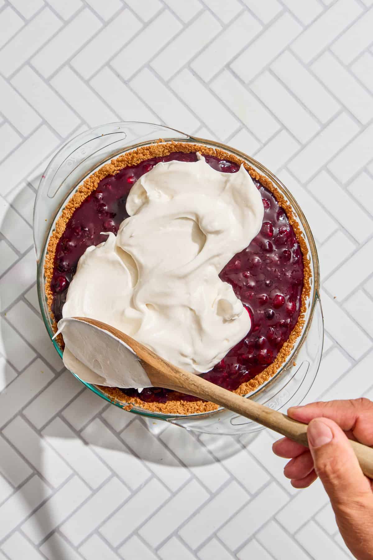 meringue being spread over the blueberry pie