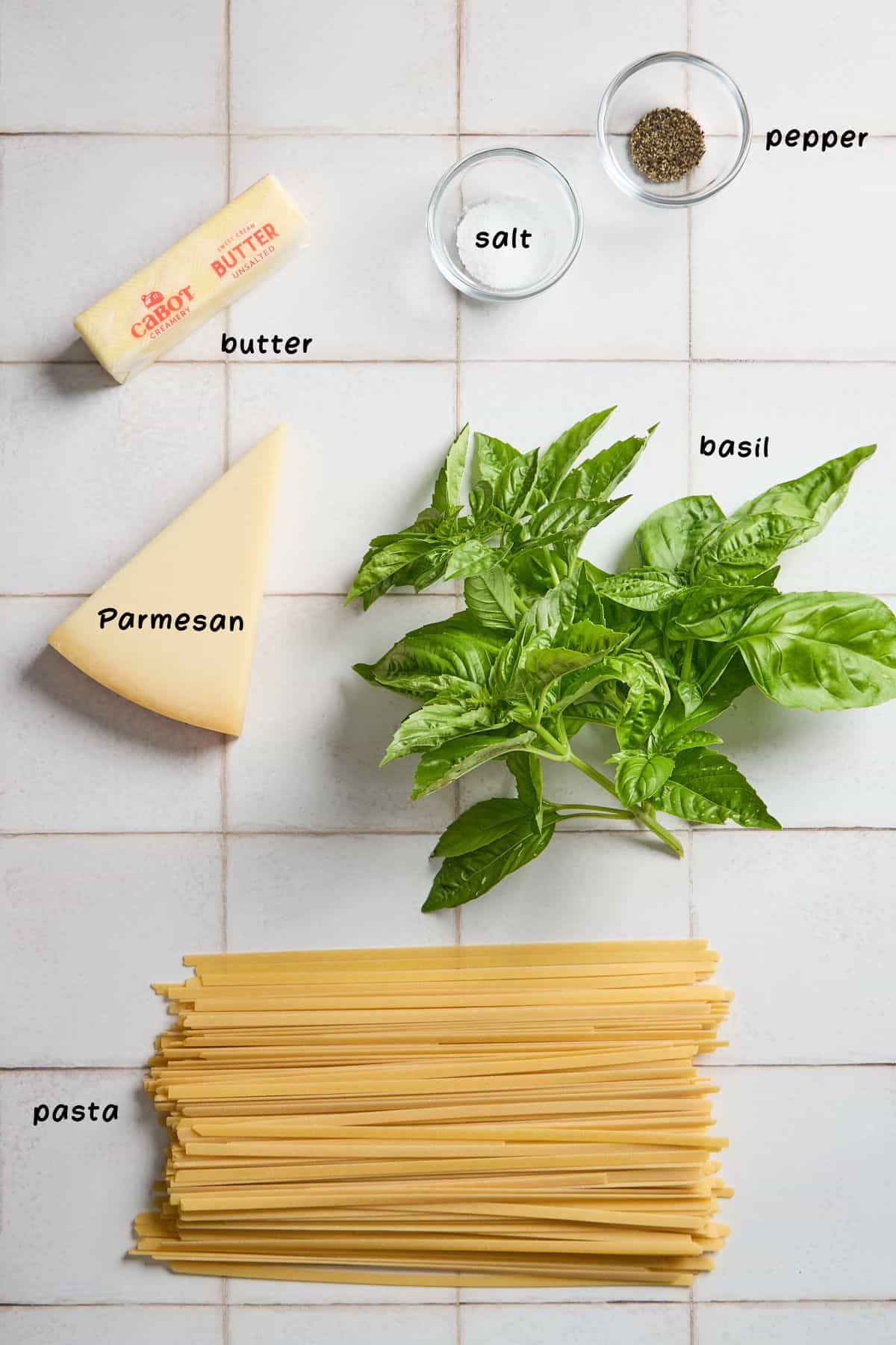 basil, parmesan, and ingredients for making the alfredo on a white tiled counter